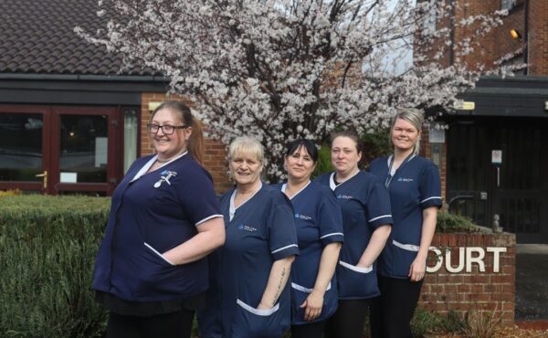 Why Our Carers Stay: Rewarding Careers in Domiciliary Care 1 Pictured is of five caring care workers outside, stood together and smiling towards the camera in their navy uniforms.